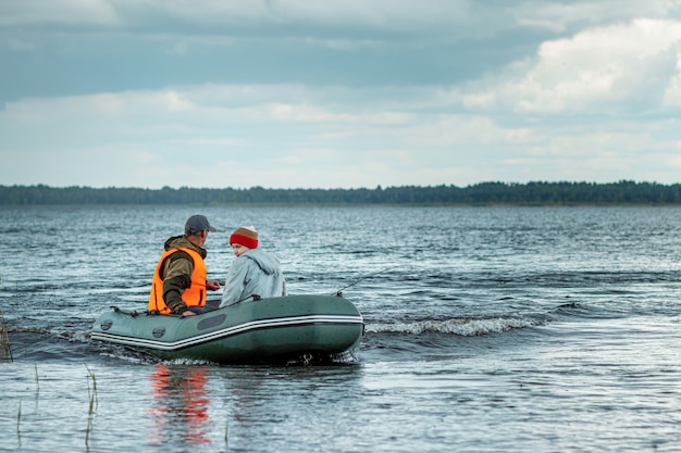 Father and son ride a motor boat on the lake.