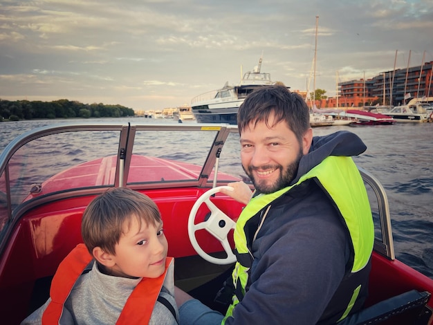 Father and son riding motor boat wearing safety vests having a ride in Neva river Saint Petersburg