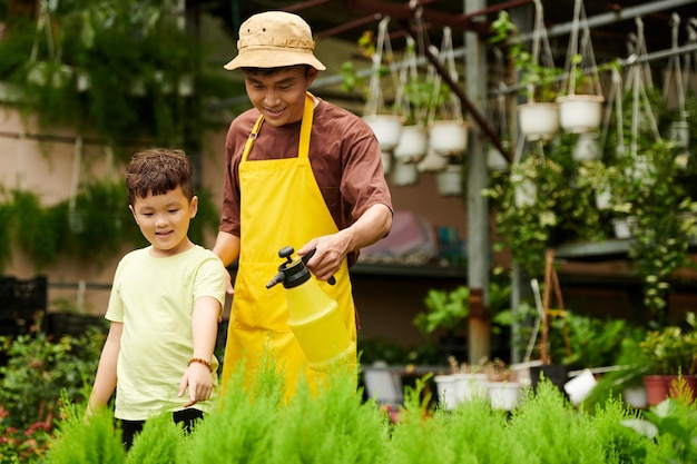 Father and Son Spraying Plants