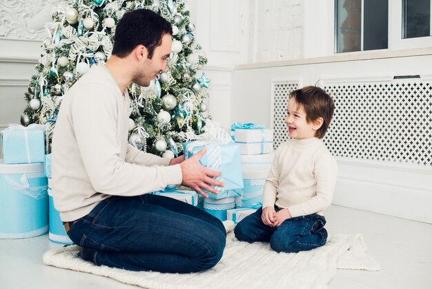 Father and son unwrapping a present lying on the floor