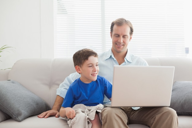 Father and son using laptop on the couch