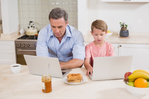 Father and son using laptop in kitchen