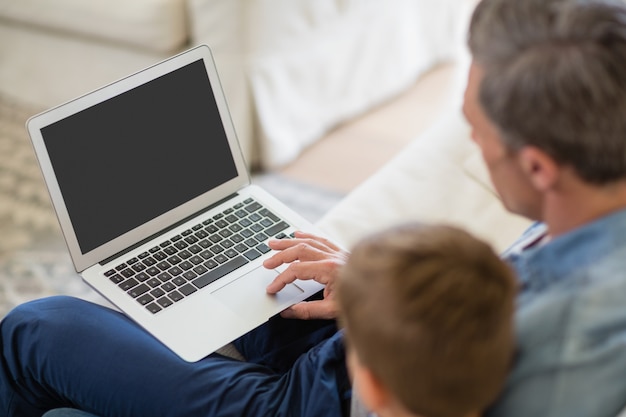 Father and son using laptop in living room