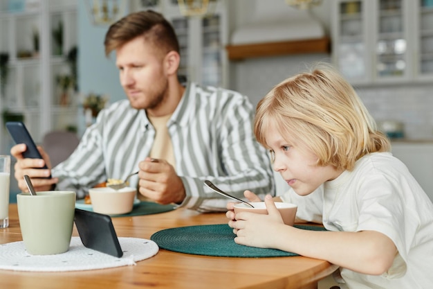 Father and Son using Phones at Breakfast