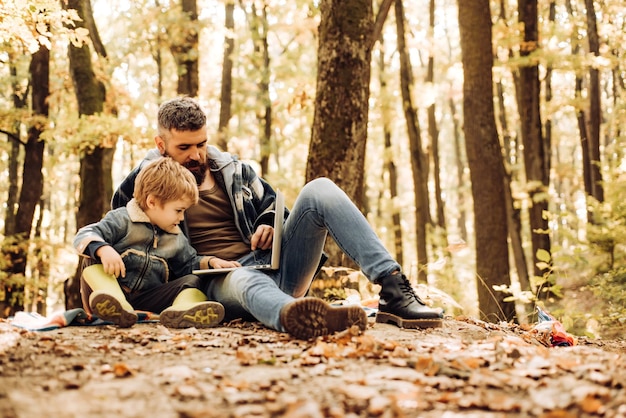 Father and son walking in autumn forest at sunset sweetheart child and bearded dad lie on fall autum