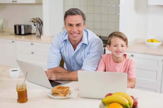 Father and son with laptop in kitchen