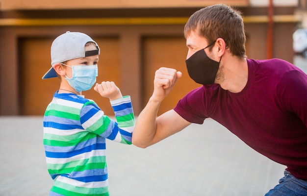 Father and son with mask bump elbows