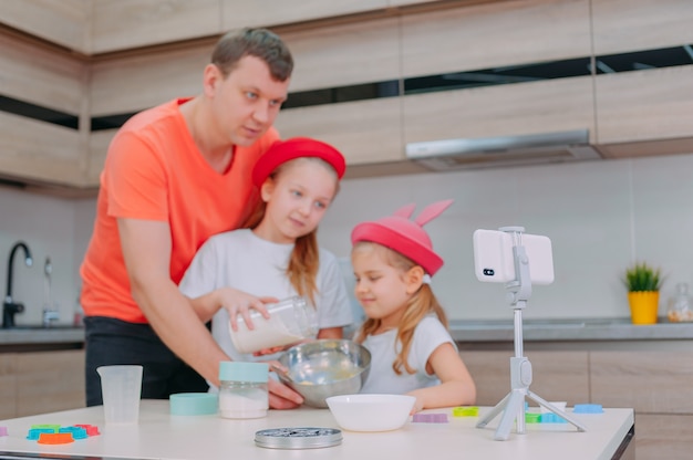 Father teaches two daughters to cook dough in the kitchen