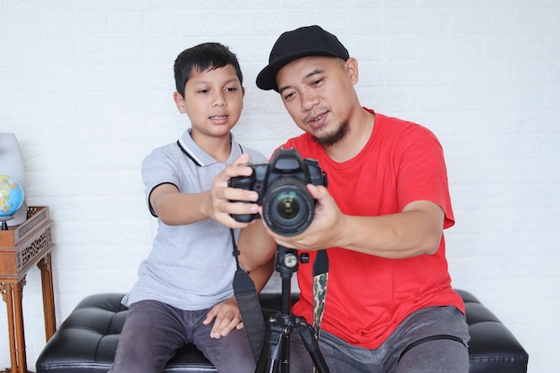 Father teaching cute little son to use digital camera for photography