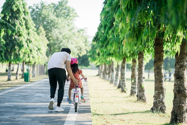 Father teaching daughter to ride bike in the park