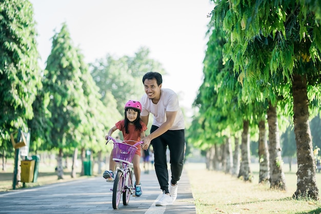 Father teaching daughter to ride bike in the park