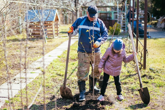 Father teaching his daughter how to plant a new tree in spring