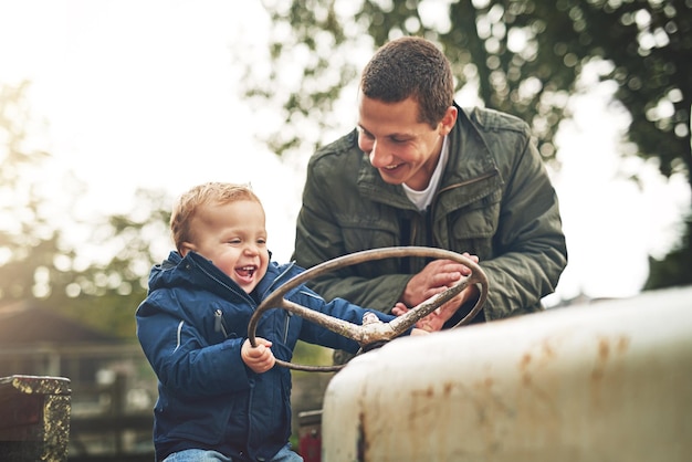 Father and teaching son to drive tractor for farming education learning and bonding in nature Excited dad and kid with smile on harvest vehicle for lesson agriculture knowledge and fun together