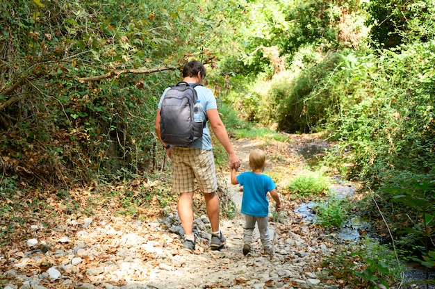 father together his kid son and family on a hike through a mountain gorge overcomes obstacles. vacation in the new normal.