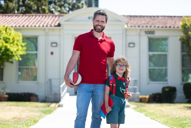 Father walking son to school parent and pupil of primary school schoolboy with backpack