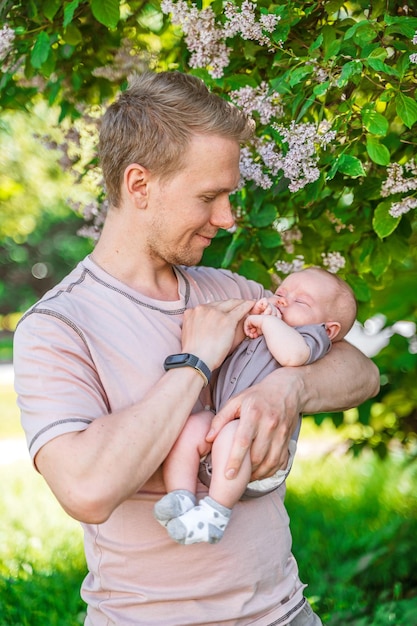 A father walks in a summer park with his baby kid