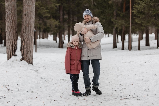 Father walks with his little daughters in winter forest