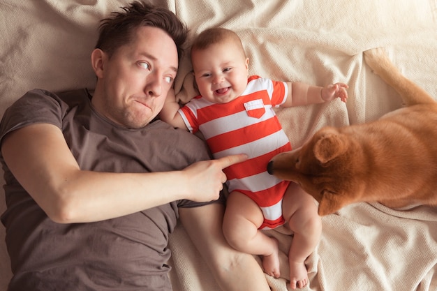 Father with baby son and pet Shiba Inu Dog having fun and playing at home, top view.