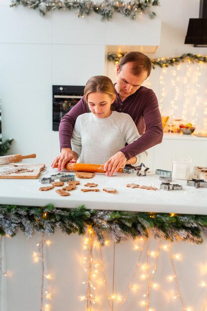 Father with daughter cooking making gingerbread, cutting cookies of gingerbread dough, having fun.