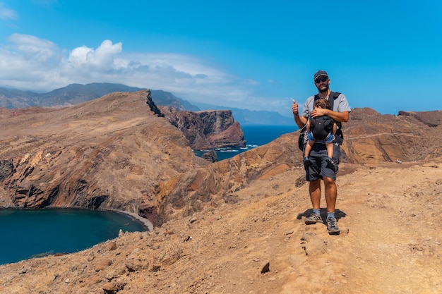 A father with his baby in summer in Ponta de Sao Lourenco looking at the landscape and the sea coast of Madeira