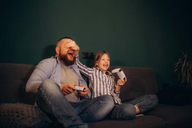 Father with his little daughter playing video game at home