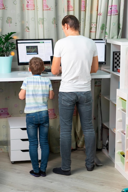 Father with kid working from home at standing desk during quarantine Freelancer with kids working from home High standing desk table comfortable for healthy back