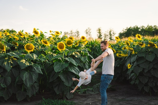 Father with little baby son in sunflowers field during golden hour Dad and son are active in nature