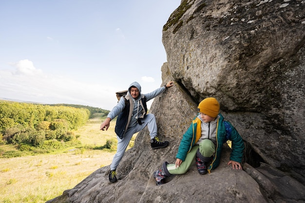 Father with son climbing big stone in hill Pidkamin Ukraine