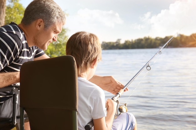 Father with son fishing from riverside