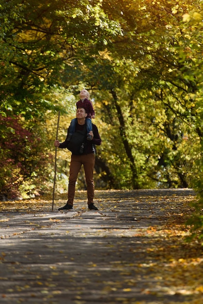 Father with son on his shoulders walking in the autumn park.