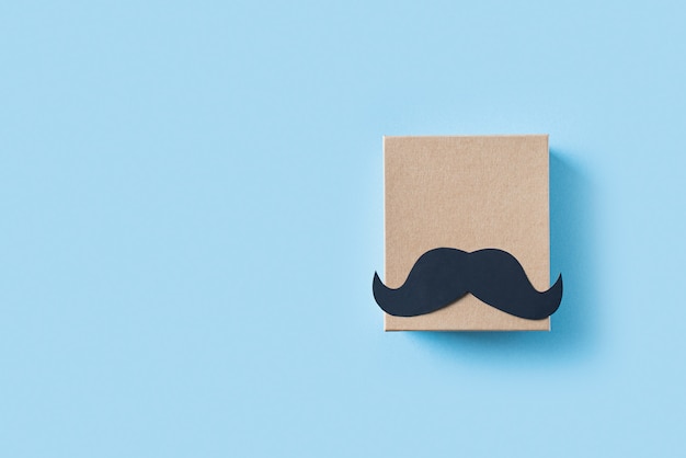 Fathers day concept with gift  box and mustache on blue background