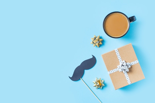 Fathers day concept with gift  box, tie and mustache on blue background