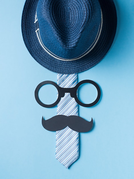 Fathers day concept with hat, glasses and tie on blue background