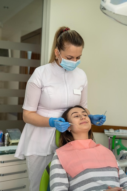 Feamle dentist using dental mirror and stainless steel tools doung examined teeth her patient Caries protection Tooth decay treatment