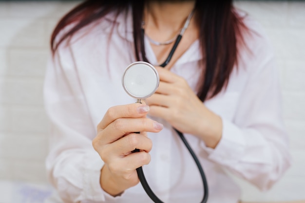 Feamle doctor with stethoscope examining red heart.