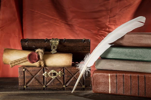 Feather near sealed scroll in old chest and vintage books