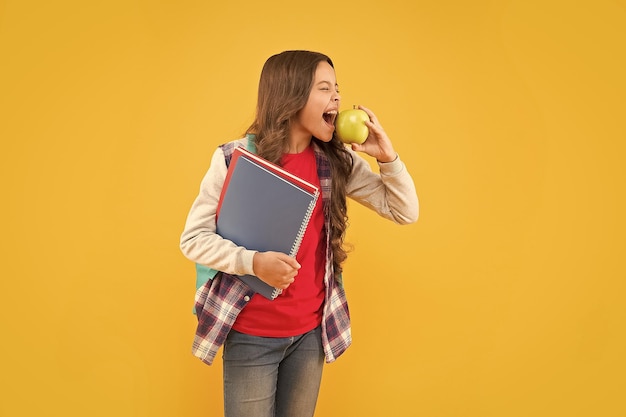 Feed your imagination Little girl bite apple yellow background School snack Healthy eating habits Diet and health Childhood imagination Imagination and fantasy She is a hasty reader