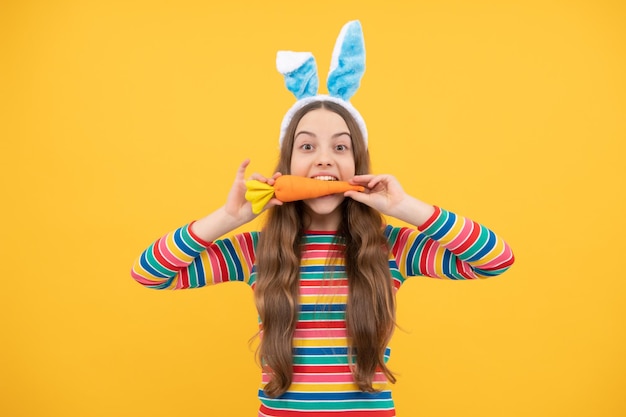 Feel the hunger easter bunny hunt just having fun happy childhood cheerful bunny kid bite carrot happy easter holiday funny child hold carrot teenager girl wear rabbit ears