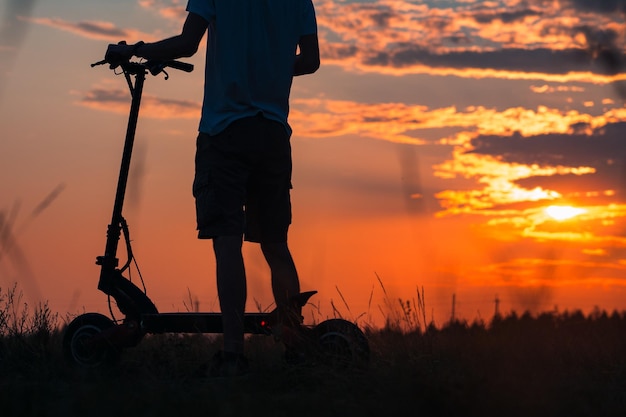 The feeling and concept of freedom Riding an electric scooter A young man on a scooter enjoys the sunset