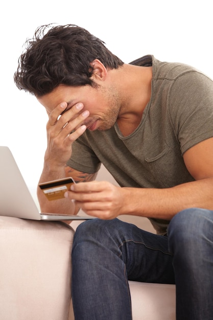 Feeling the credit crunch A young man with his head in his hand looking upset while holding his credit card