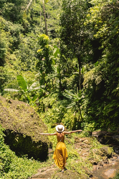 Feeling freedom. Slim woman standing with face to jungles while shooting her travel blog