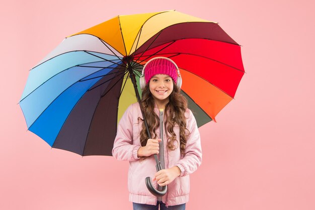 Feeling good Girl having fun walking wireless headphones under colorful umbrella Fall leisure Music always with me Every day fun Child enjoying simple things Entertain yourself Fun concept