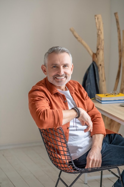 Feeling good. A gray-haired man in orange shirt looking happy