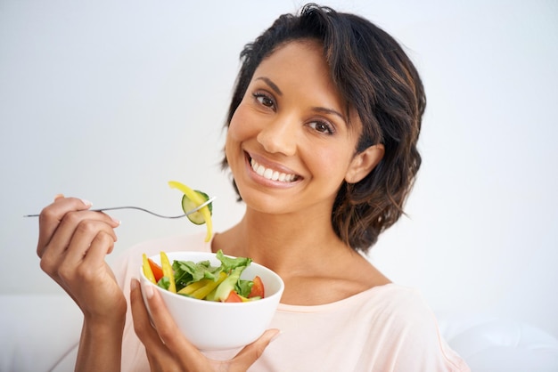 Feeling good starts with eating right Portrait of a young woman enjoying a salad at home