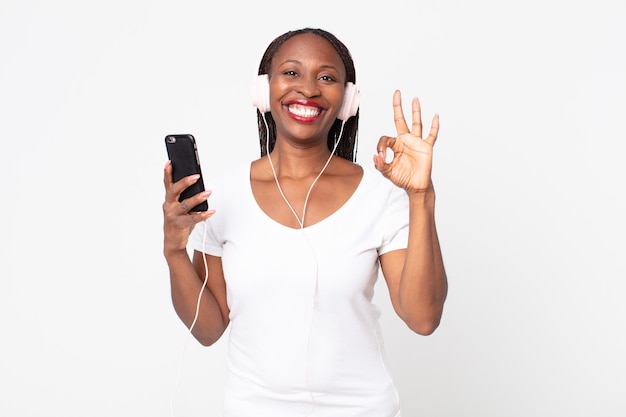 Feeling happy, showing approval with okay gesture with headphones and a smart phone