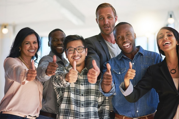 Feeling positive about their career choice Portrait of a group of happy creative colleagues showing a thumbs up together in the office