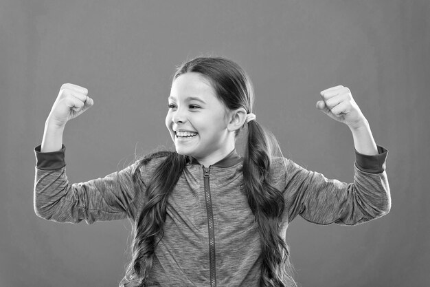 Photo feeling strong child cute girl show biceps power and strength girls rules concept upbringing advices for girls strong and powerful raising strong kids satisfied with her strong healthy body