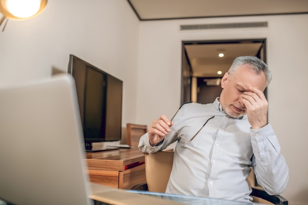 Feeling tired. Gray-haired man feeling tired after a long working day