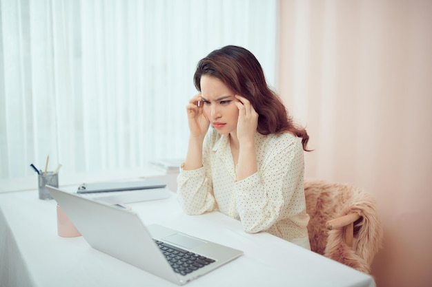 Feeling tired and stressed. Young Asian woman sitting with eyes closed from exhaustion and tireness during working at home using laptop