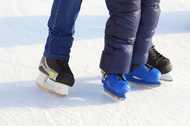 Feet of different people skating on the ice rink